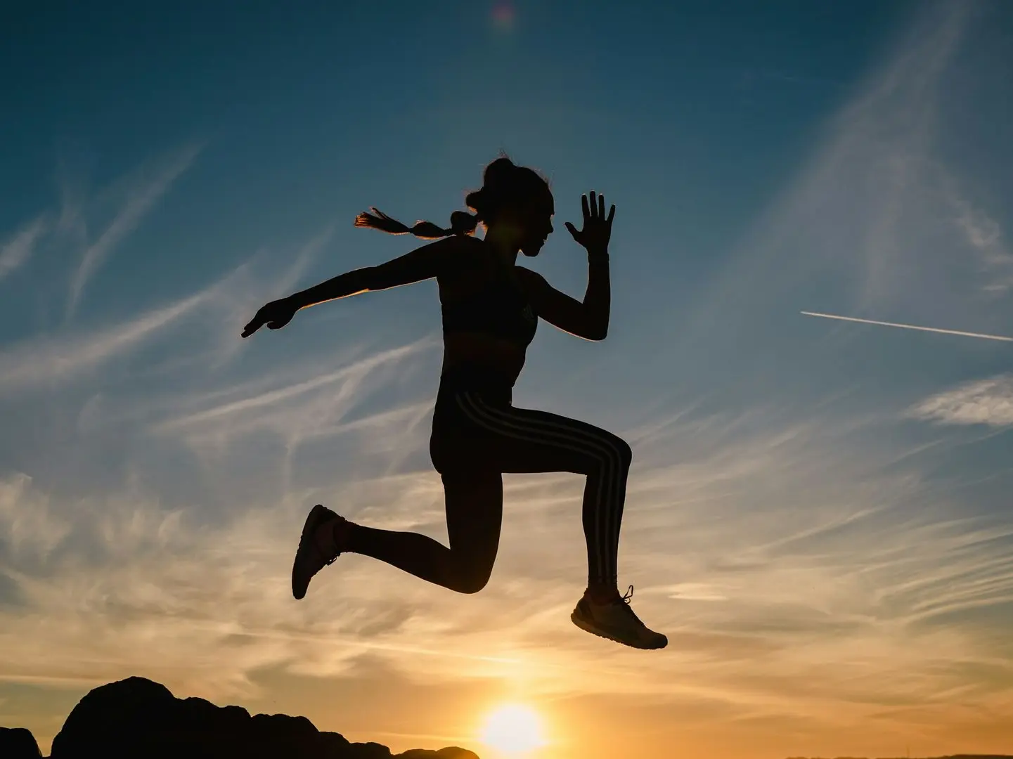 a silhouette of a person jumping in the air
